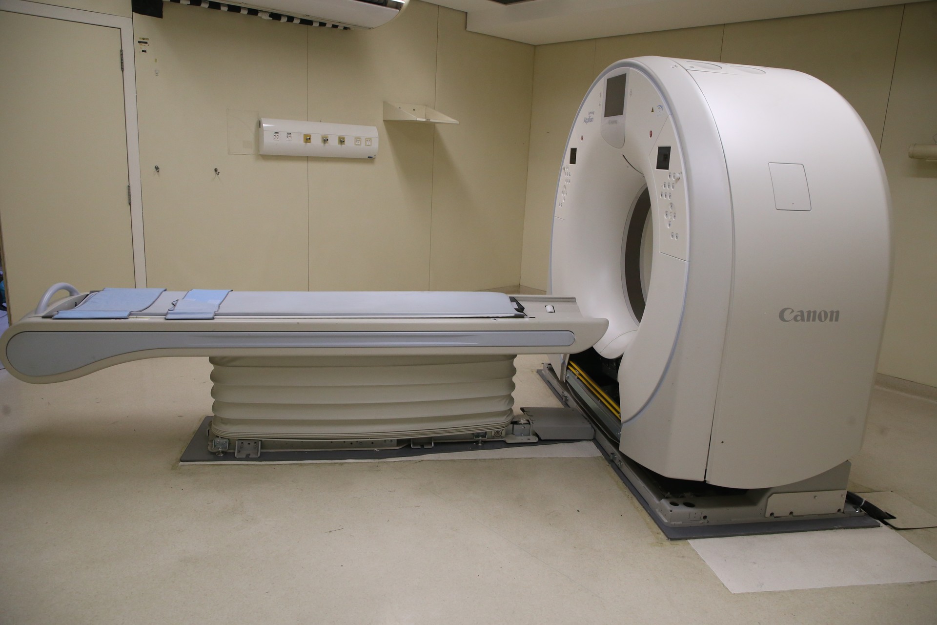 An empty Canon CT scanner and patient table in an imaging room.