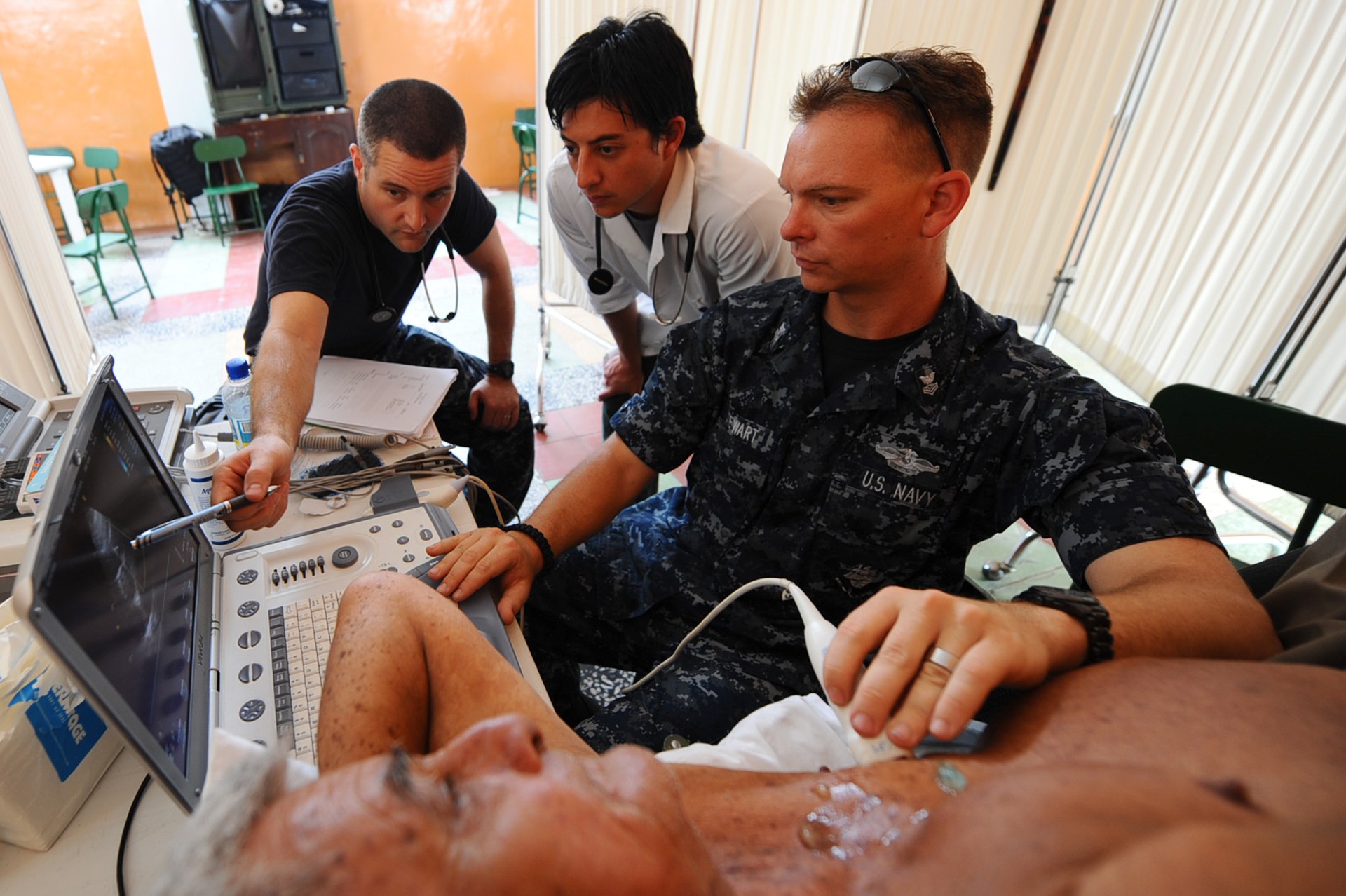 Clinicians examine an ultrasound display while performing a cardiac ultrasound examination.